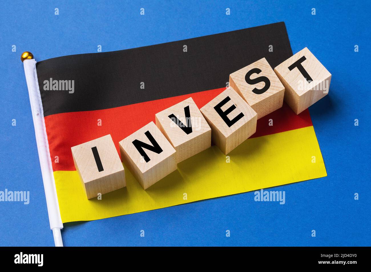 Cubos de madera con texto y una bandera sobre un fondo coloreado, el concepto de inversión de Alemania Foto de stock