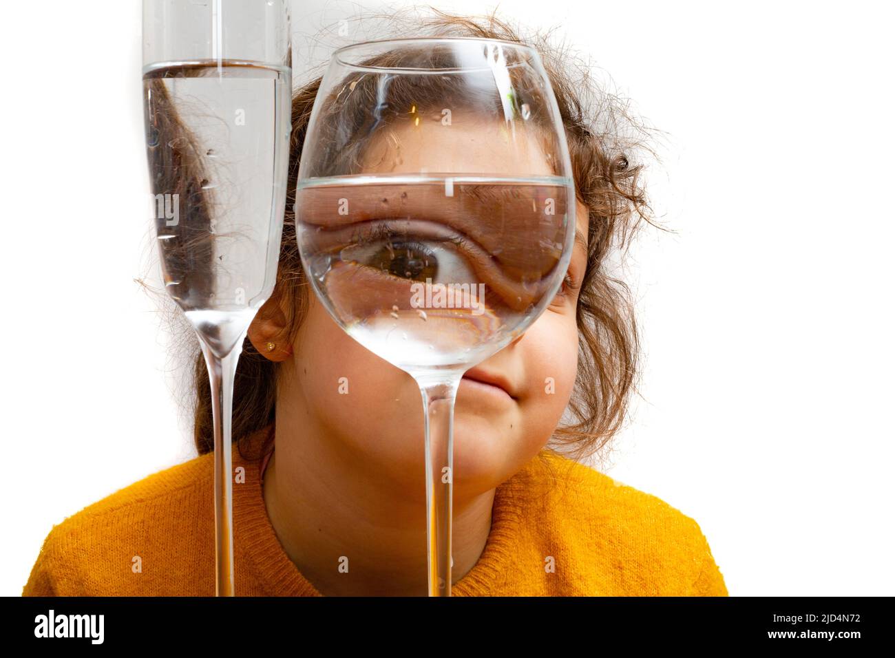 Retrato de niño de moda, el ojo mira a través del vaso de agua. Distorsión de objetos, concepto de ilusión óptica. Arte contemporáneo minimalista de alta calidad Foto de stock