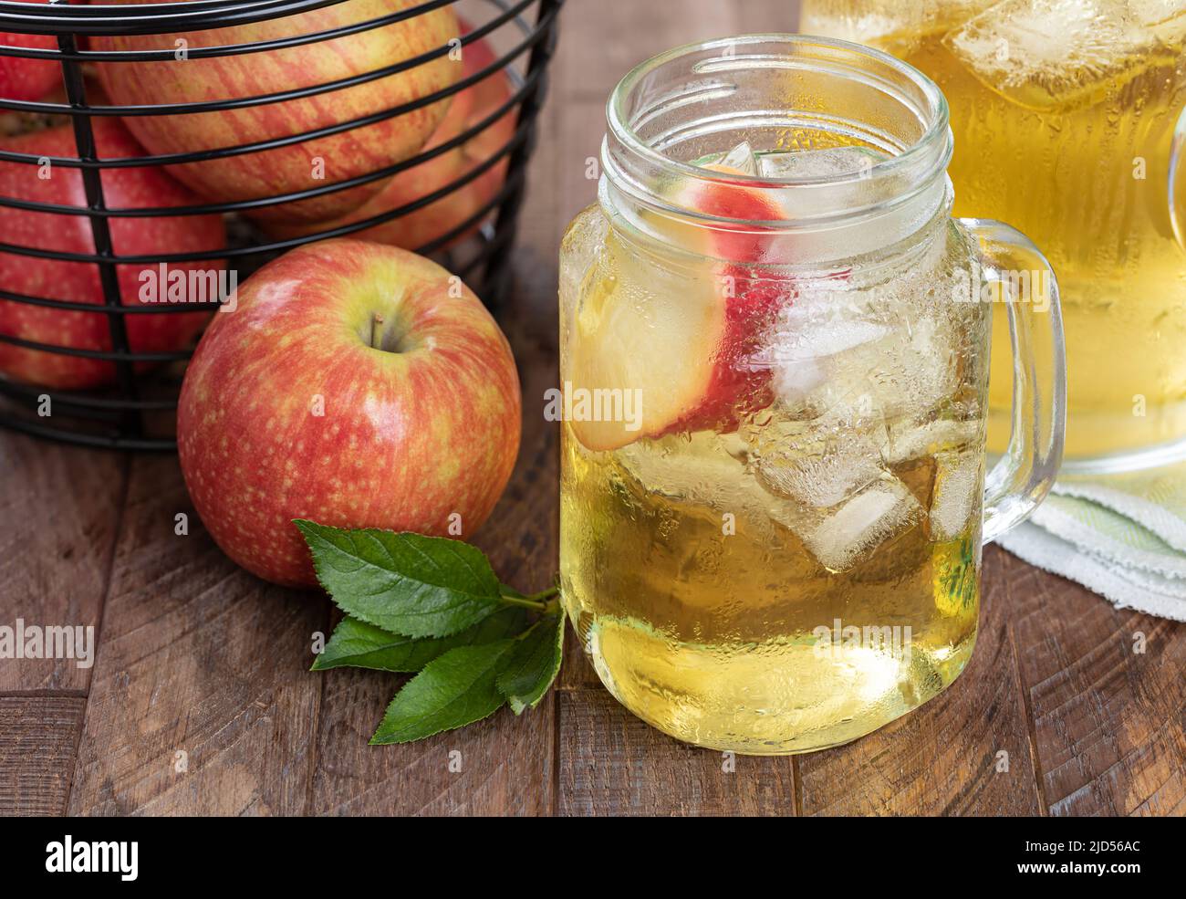 Vaso de jugo de manzana, rodaja de manzana y hielo con manzanas rojas de fressh sobre una mesa de madera Foto de stock