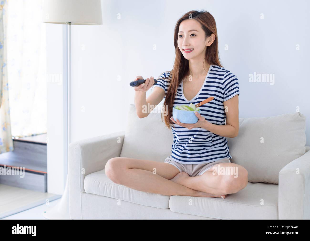 Feliz mujer joven viendo la televisión en casa Foto de stock