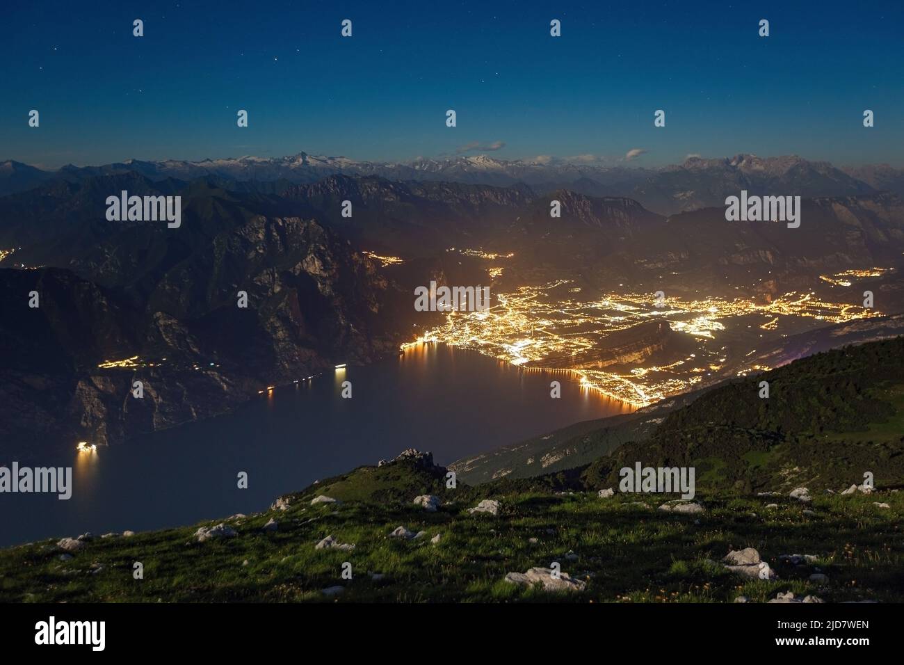 Luz de la Luna en el Lago de Garda desde la cima del Monte Altissimo di Nago. Luces nocturnas de la ciudad de Riva del Garda. Trentino. Prealpi Gardesane. Italia. Foto de stock