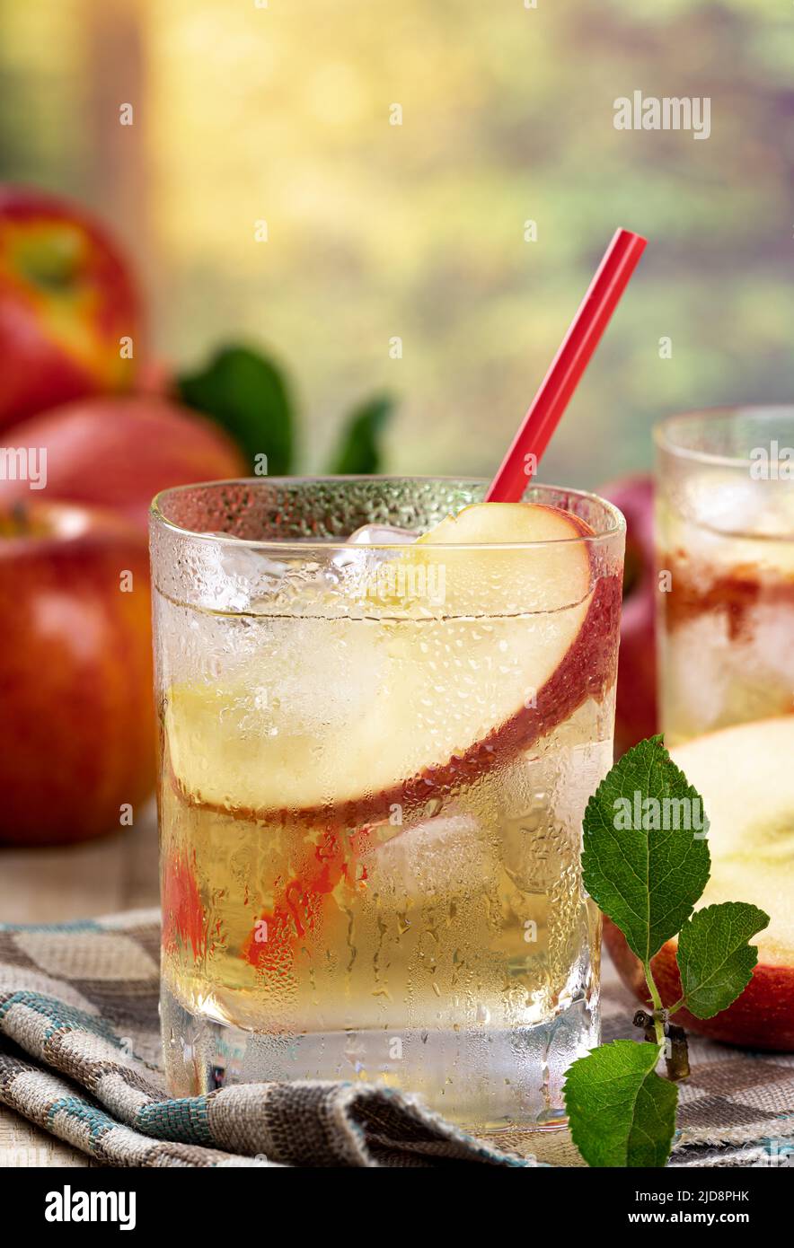 Refrescante jugo de manzana con rodaja de manzana y hielo en un vaso con fondo de verano Foto de stock