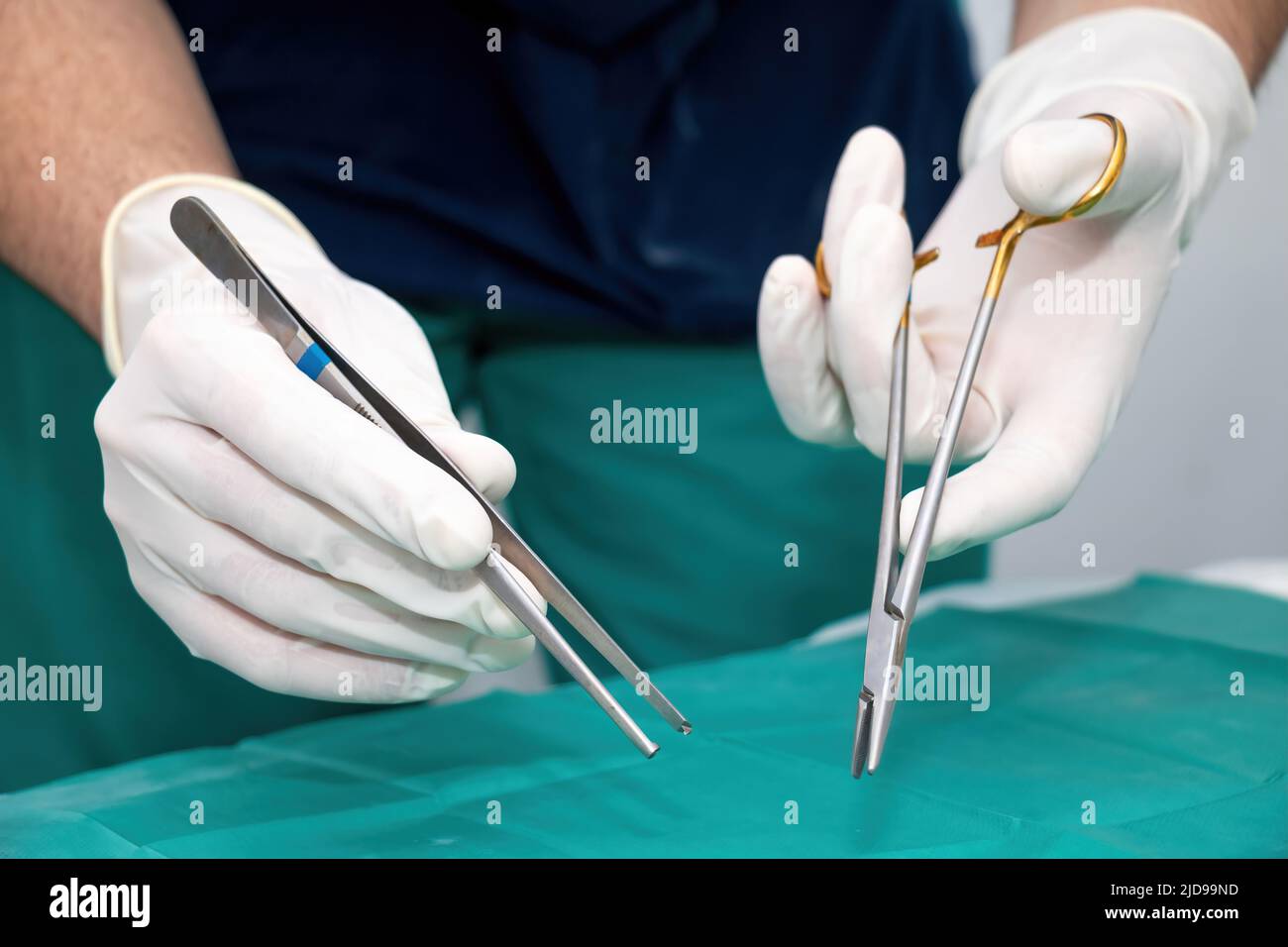 Cirujano médico en uniforme y con guante desechable en la mano sujetando  pinzas y tijera sobre tela verde. Equipo médico de herramienta de acero  inoxidable para SUR Fotografía de stock - Alamy