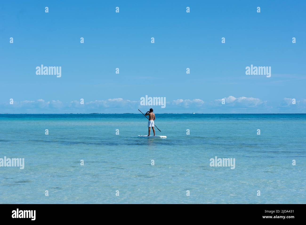 Un hombre haciendo paddle en el Mar Caribe cerca de la playa Isla Mujeres en México Foto de stock