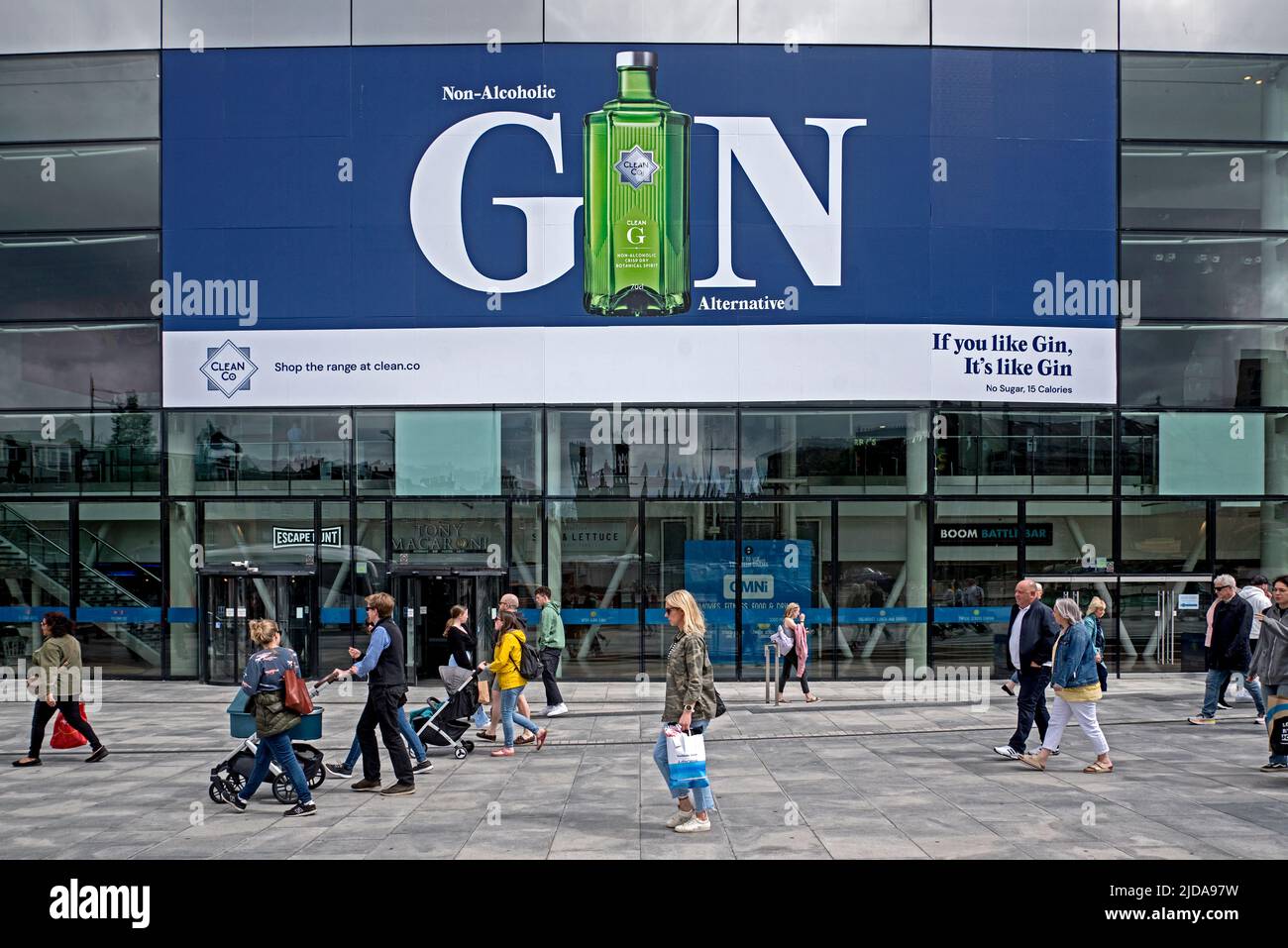 Los compradores caminan por un anuncio de ginebra no alcohólica en el Omni Center en Edimburgo, Escocia, Reino Unido. Foto de stock