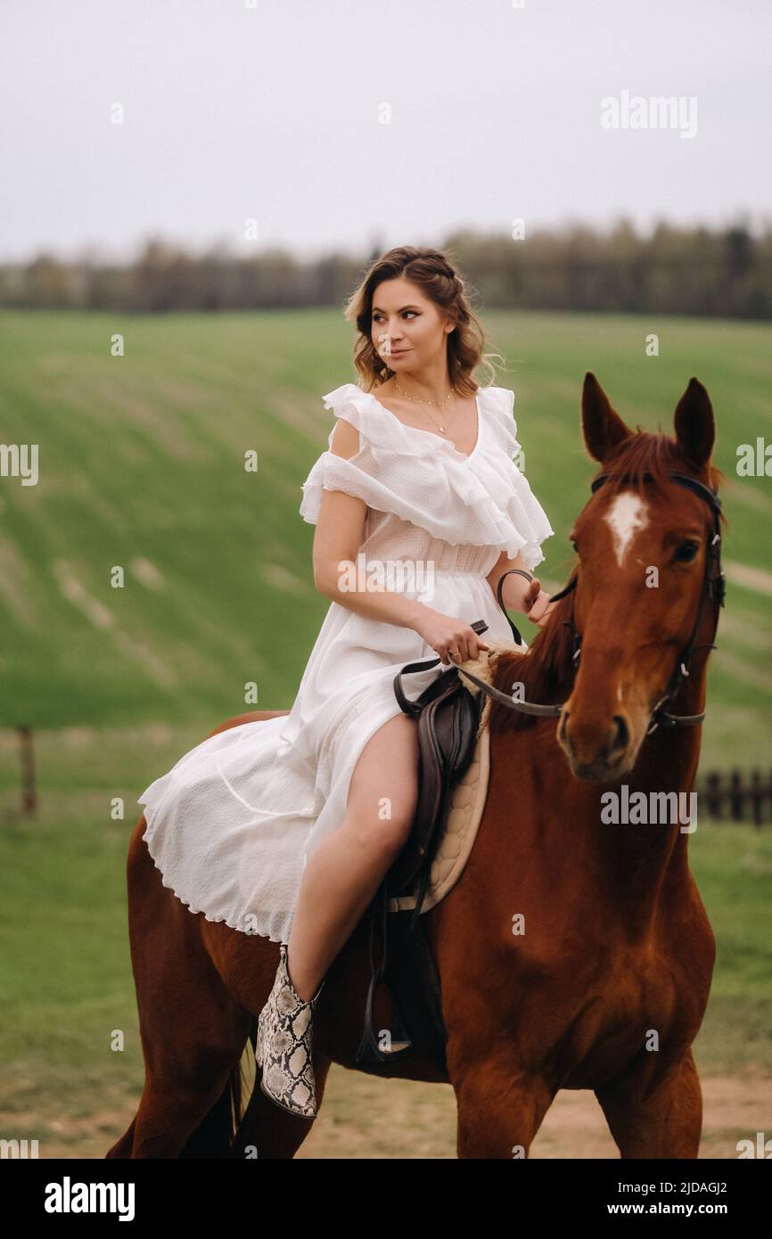 Una mujer en una desnuda blanca montando a caballo en un campo Fotografía  de stock - Alamy