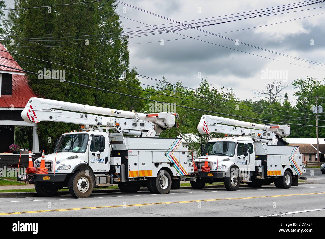 Dos camiones de servicio de National Grid equipados con elevadores de pluma para trabajar en líneas eléctricas, estacionados en Speculator, NY, EE.UU Foto de stock