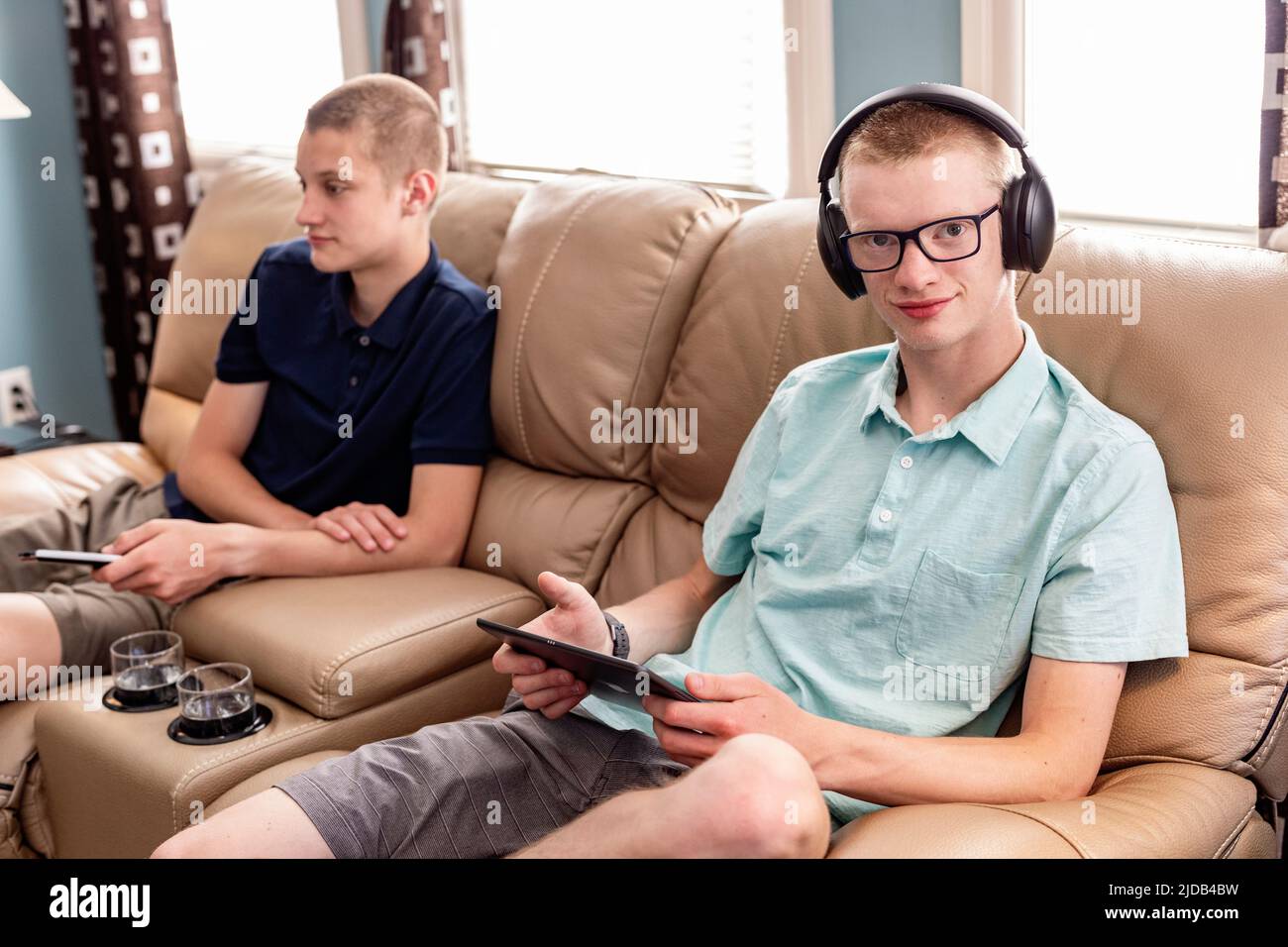 Jóvenes hermanos adultos usando tableta y teléfono inteligente juntos en casa; Edmonton, Alberta, Canadá Foto de stock