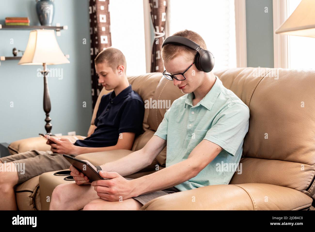 Jóvenes hermanos adultos usando tableta y teléfono inteligente juntos en casa; Edmonton, Alberta, Canadá Foto de stock