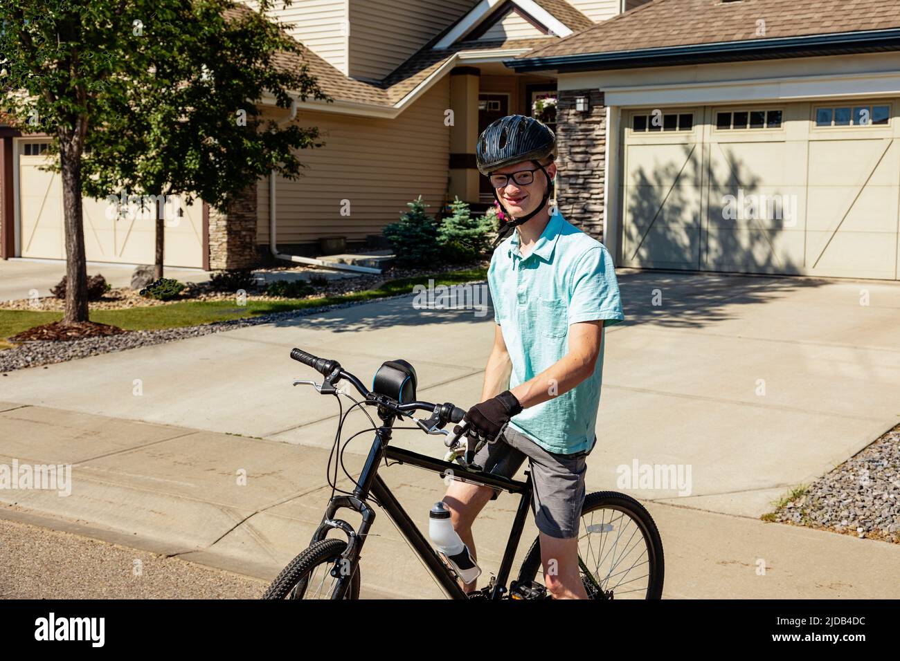 Joven posando en su bicicleta en una calle residencial; Edmonton, Alberta, Canadá Foto de stock