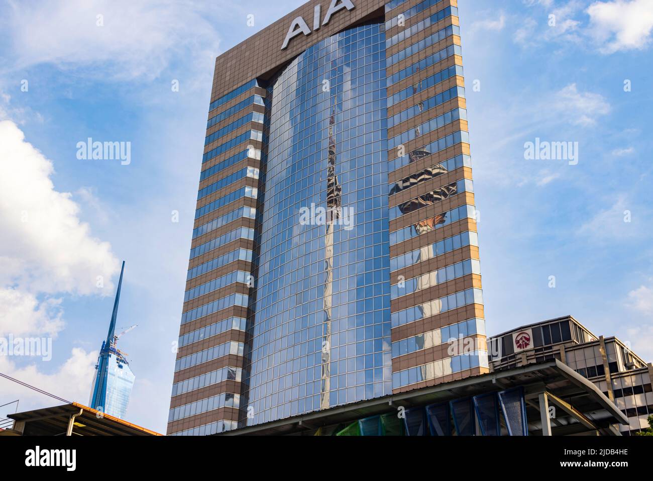 Kuala Lumpur, Malasia - junio de 18. 2022: Torre Menara que se refleja en la fachada de cristal del edificio AIA. En el fondo el rascacielos Merdeka 118. Foto de stock
