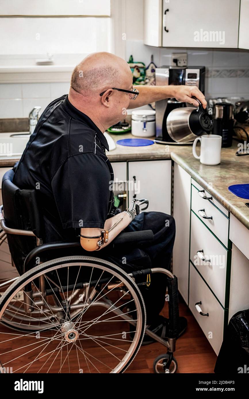 Hombre con amputaciones de doble extremidad vertiendo café en la cocina en casa; St. Albert, Alberta, Canadá Foto de stock