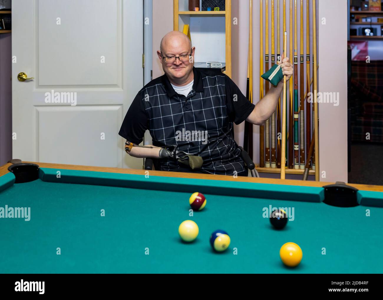 Hombre con amputaciones de doble extremidad jugando un juego de billar en casa; St. Albert, Alberta, Canadá Foto de stock