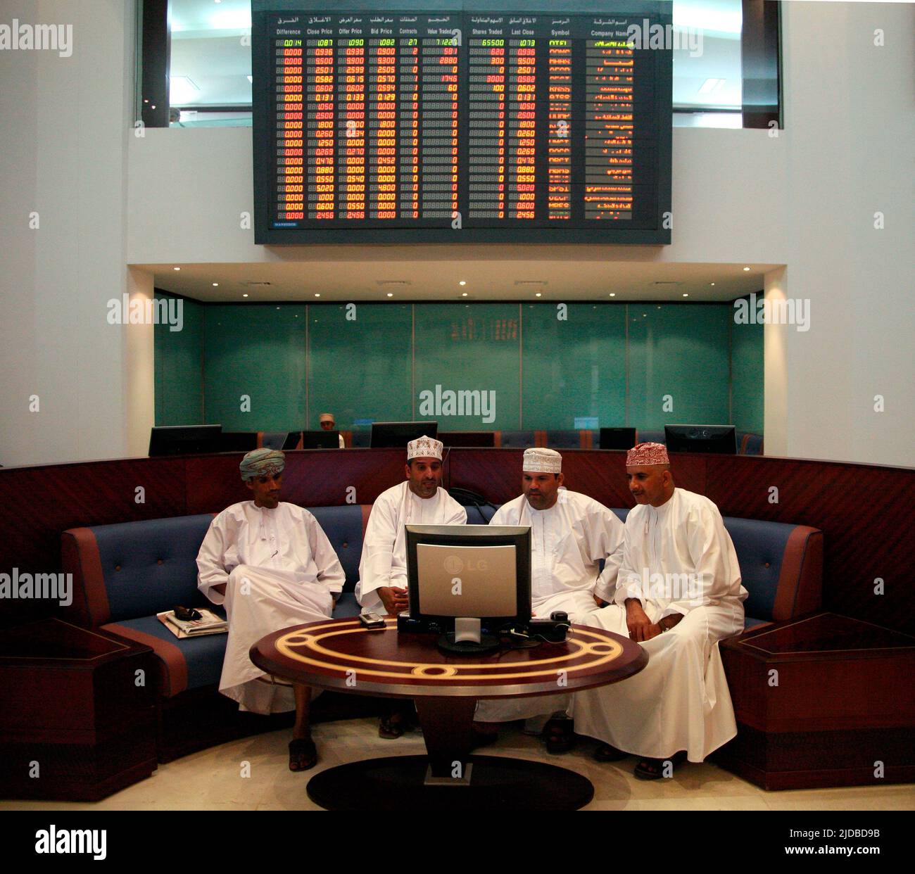 Hombres omaníes que comprueban los precios de las acciones en el mercado de valores de Muscat Foto de stock