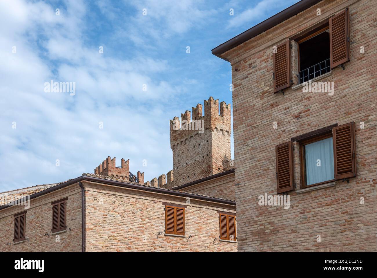 Gradara, Italia, con vistas a las tradicionales casas de ladrillo con las torres de las murallas medievales en el fondo, Foto de stock