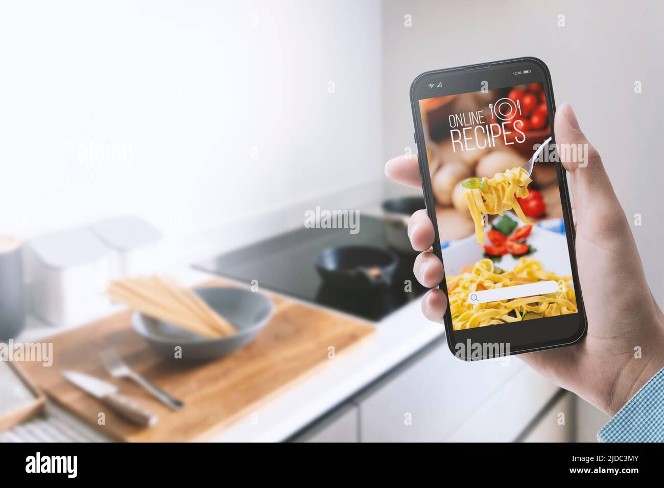 Mujer preparando una comida en su cocina, está buscando recetas saludables en una aplicación de cocina utilizando su smartphone, POV shot Foto de stock