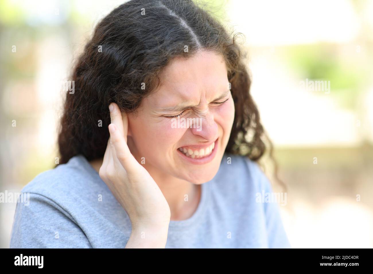Mujer estresada quejándose sufriendo dolor de oído en la calle Foto de stock