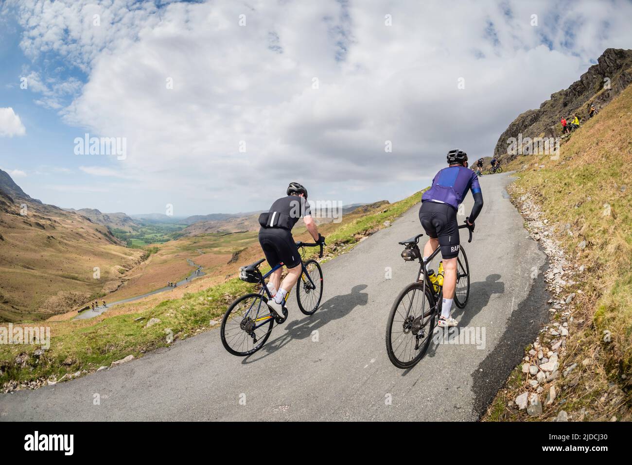 Dos ciclistas subiendo por Hardknott Pass en el Fred Whitton Challenge deportivo de ciclismo que se celebra en el distrito de los lagos ingleses, Reino Unido. Foto de stock