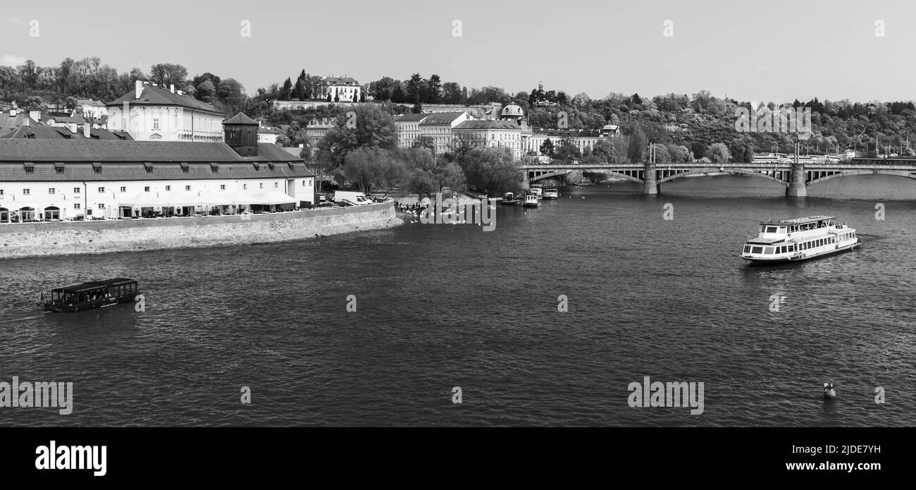 El barco turístico navega por el río Vltava. Paisaje urbano de Praga en un día de verano. República Checa. Foto panorámica en blanco y negro Foto de stock