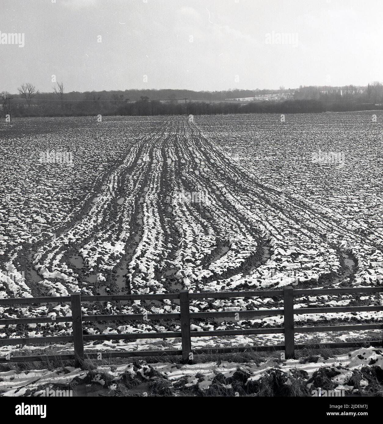 1960s, tiempo histórico, de invierno y en una granja una vista a través de un campo cubierto de nieve, con la sección media arada del suelo haciendo un patrón distintivo, Inglaterra, Reino Unido. Foto de stock