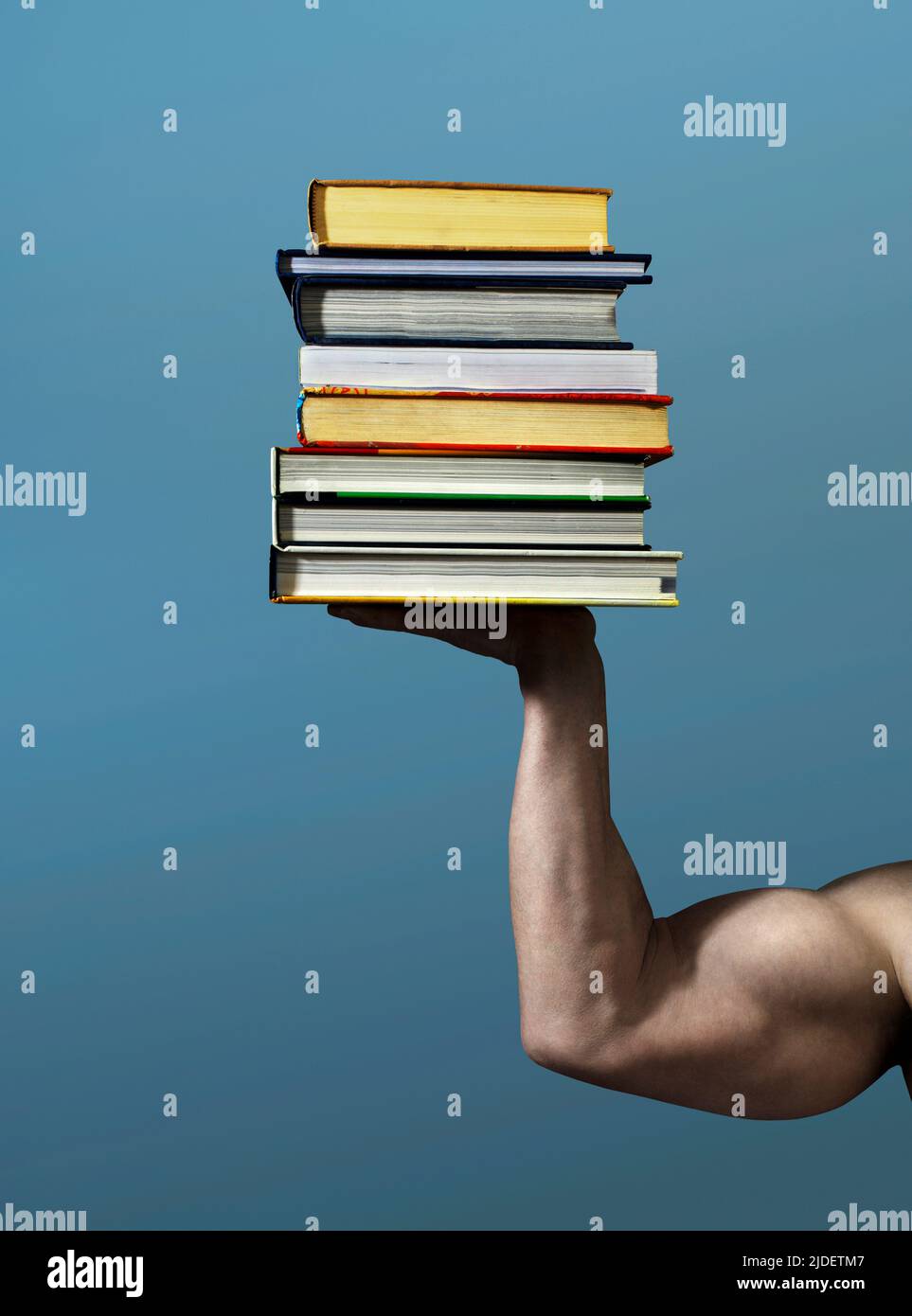 Brazo muscular sosteniendo un montón de libros Foto de stock