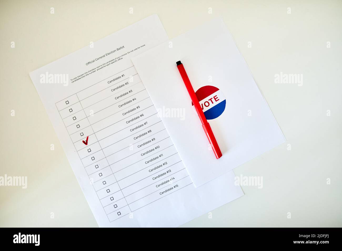 Vista superior cierre de la papeleta de votación con casilla marcada y bolígrafo rojo en mesa blanca, espacio para copias Foto de stock