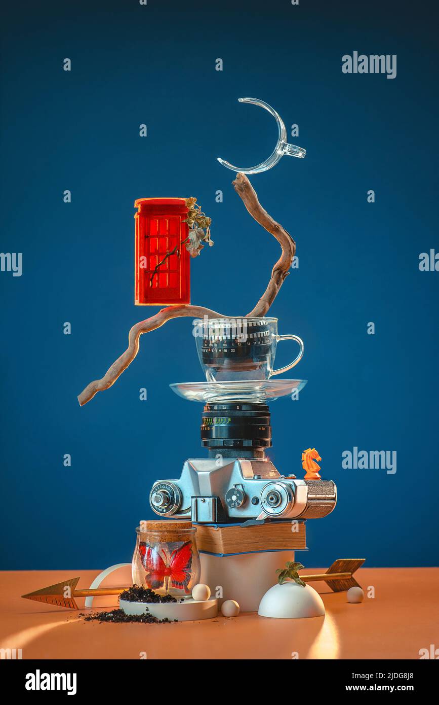 Torre de baratijas y recuerdos con una vieja cámara fotográfica, cabina de teléfonos rojos, tazas de té, figura de ajedrez y una mariposa Foto de stock