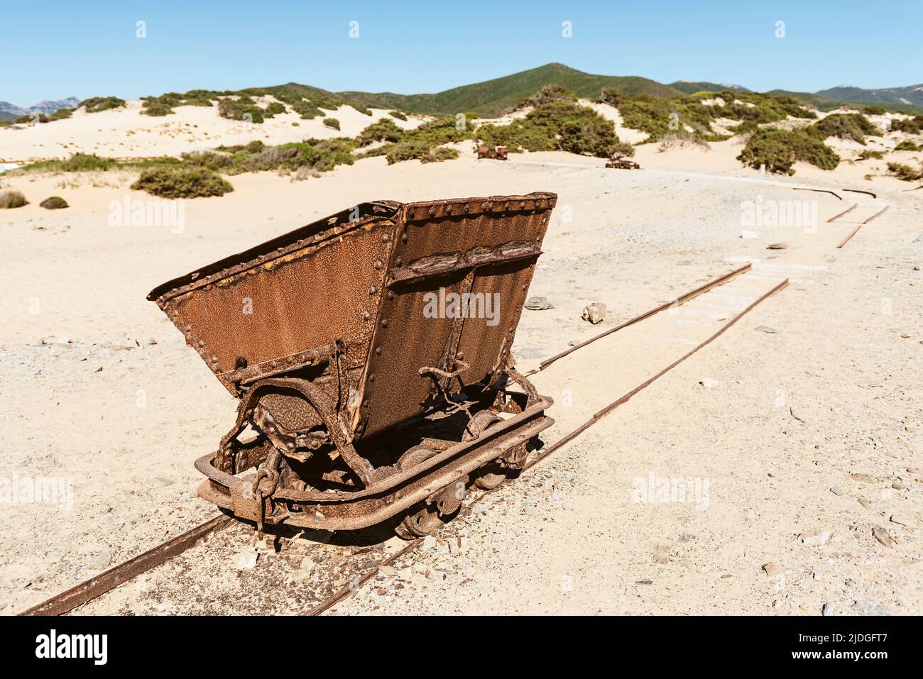 Vagones rotos oxidados y chatarra de un ferrocarril desde las minas de plomo y zinc hasta las dunas de arena cerca de la playa de Piscinas, Costa Verde, Cerdeña, Italia Foto de stock