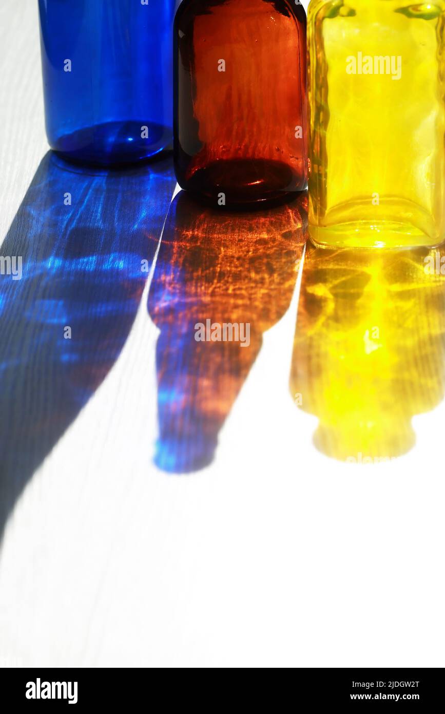 Conjunto de botellas de vidrio multicolor vacías con una buena sombra contra la luz del sol Foto de stock