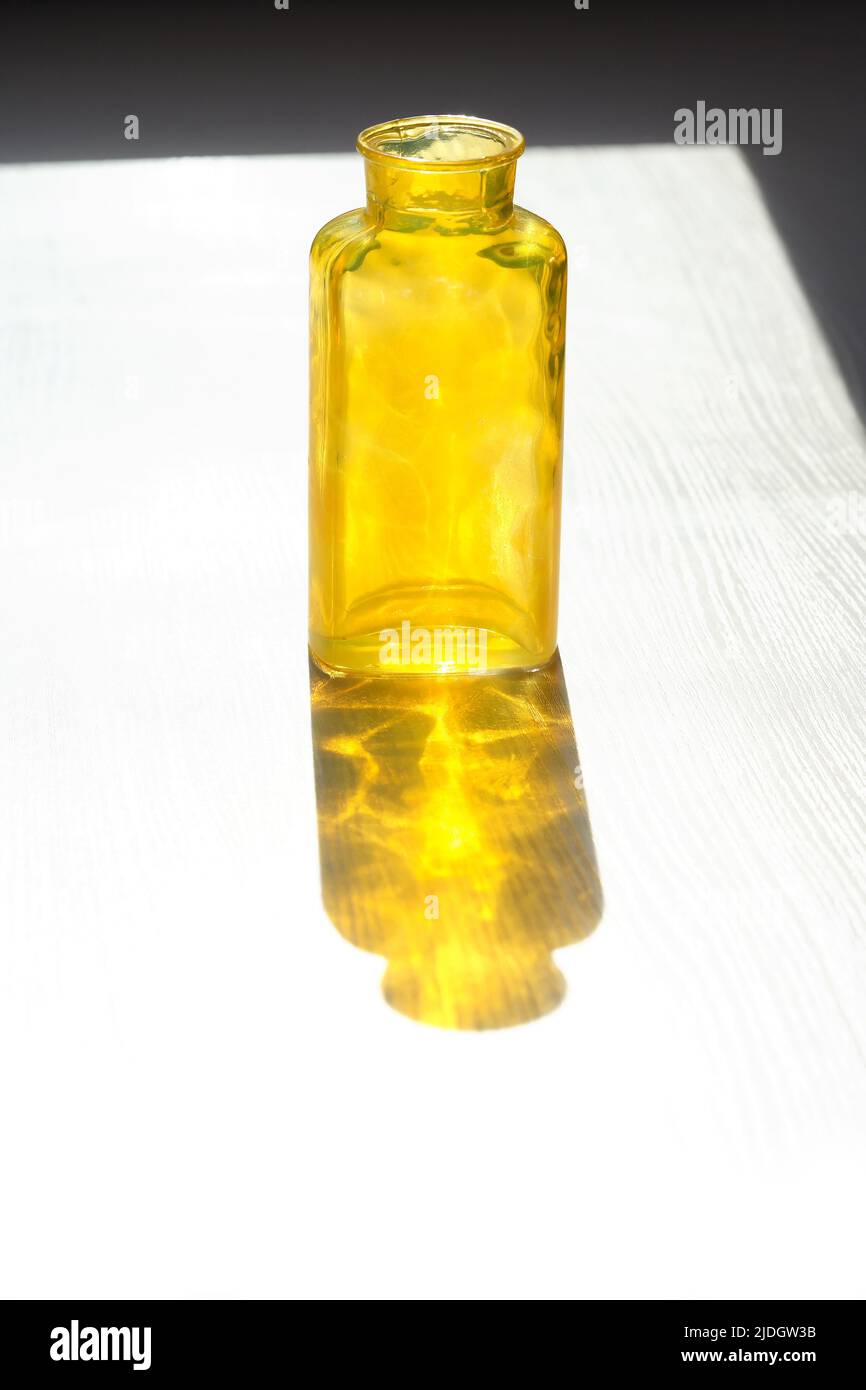 Botella amarilla de cristal vacía con buena sombra contra la luz del sol Foto de stock