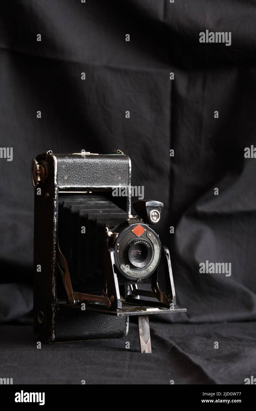 Cámara fotográfica muy vieja contra fondo de tela oscuro agradable Foto de stock