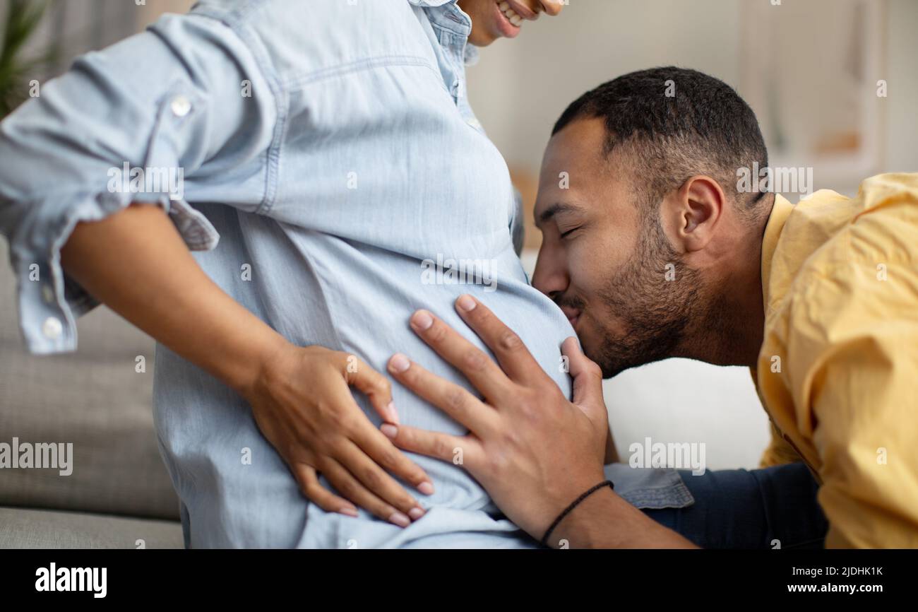 Foto recortada del marido afroamericano besando el vientre de su esposa en el interior Foto de stock