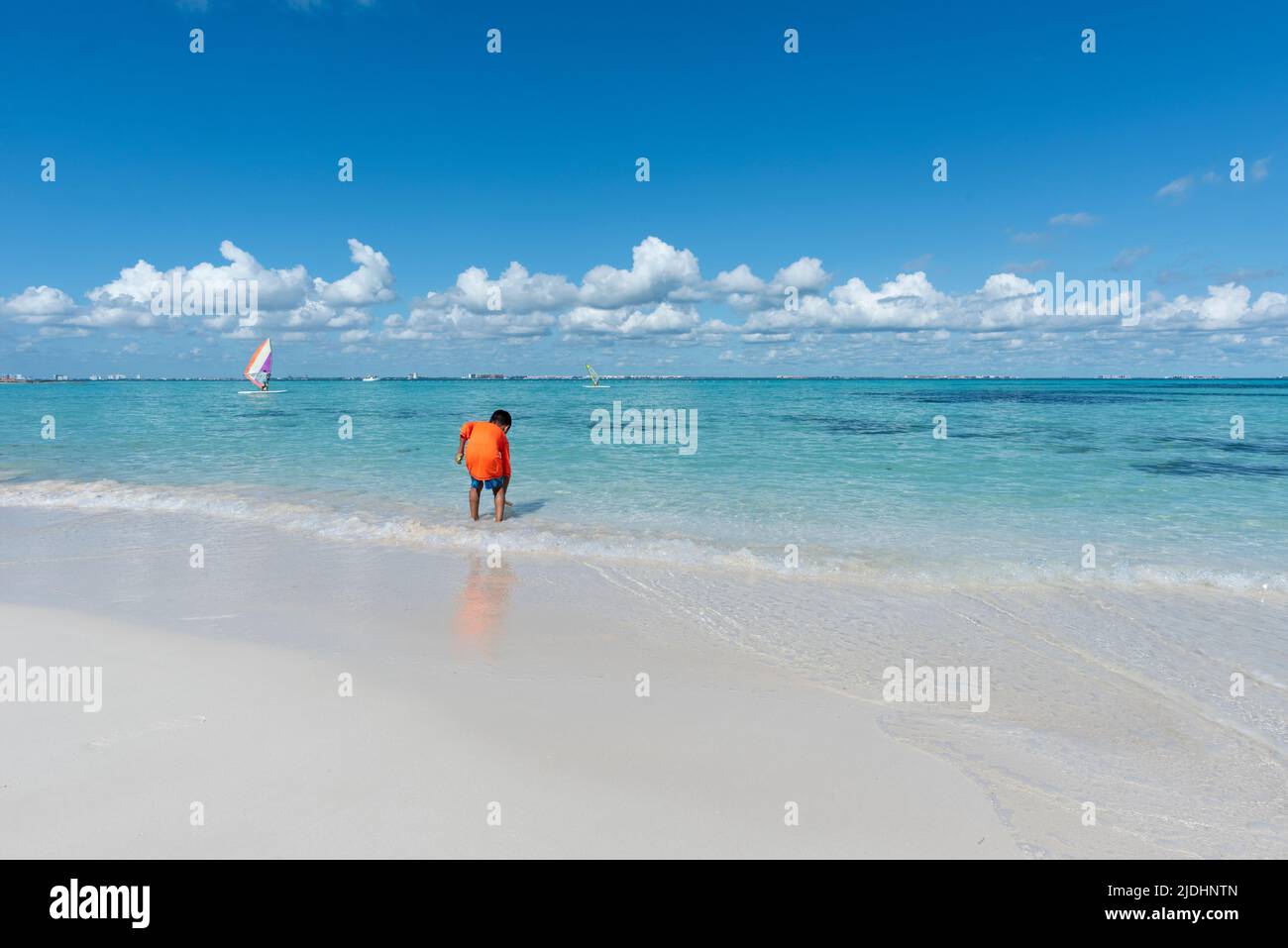 Un niño juega junto al mar en una playa tropical en Isla Mujeres México, durante las vacaciones escolares Foto de stock