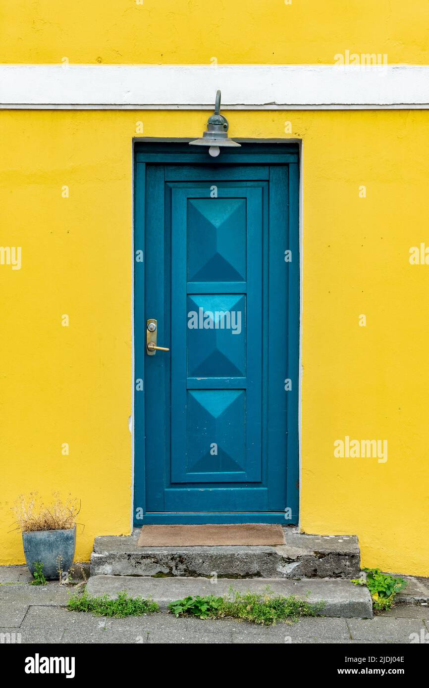 Puerta azul en una colorida casa pintada de amarillo, detalle arquitectónico en Reykjavik, Islandia Foto de stock
