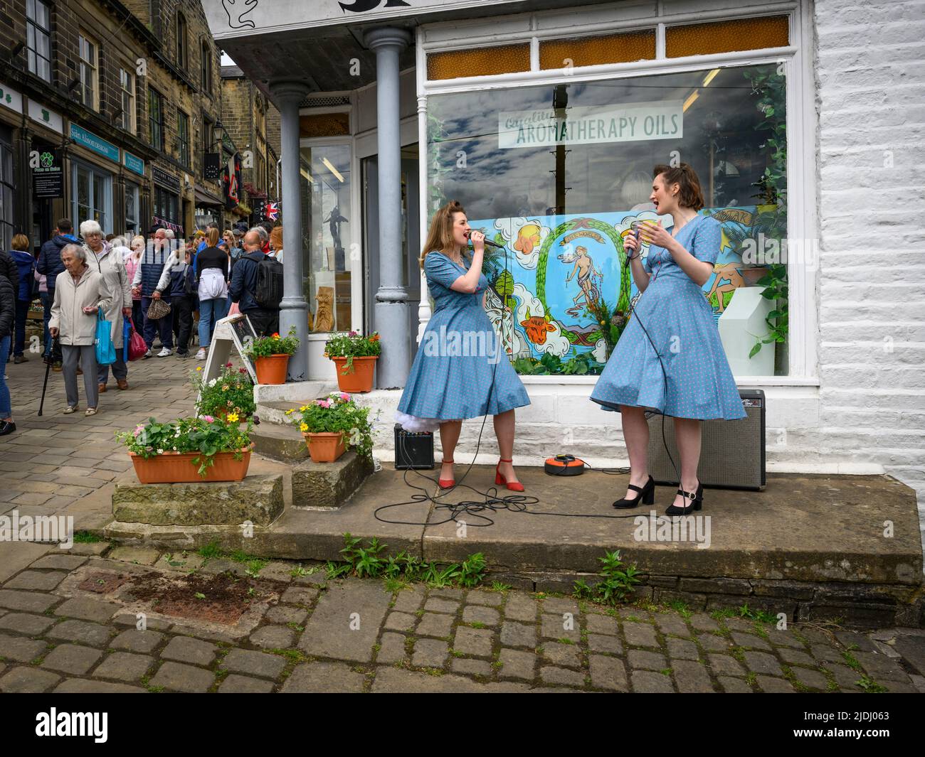 Haworth 1940 nostálgico acontecimiento retro de la historia viviente (2 dos señoras realizan música en vivo entreteniendo ocupado Main Street) - West Yorkshire Inglaterra Reino Unido. Foto de stock