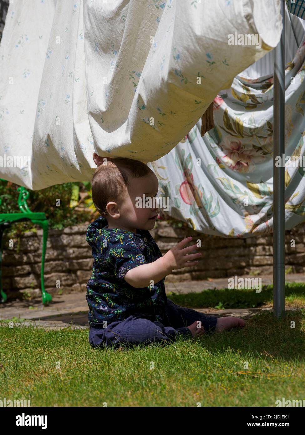 Niño jugando bajo la línea de lavado en el jardín, Reino Unido Foto de stock