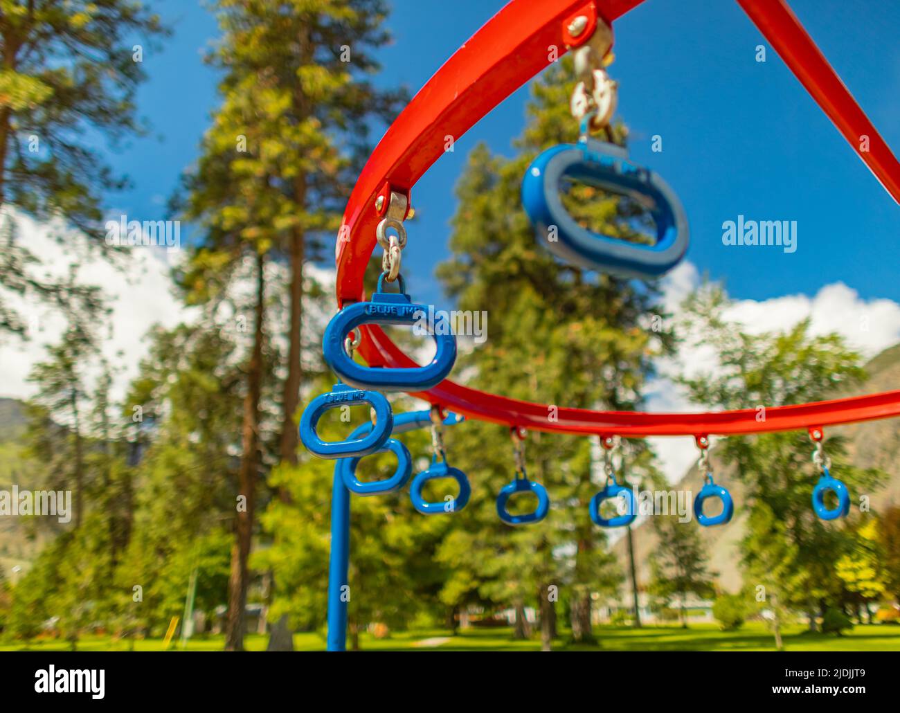 Barras colgantes de monos en un patio de recreo de verano en un parque urbano. Fila de anillos azules colgantes en un parque. Foto de la calle, actividades al aire libre, fondo borroso, nobo Foto de stock
