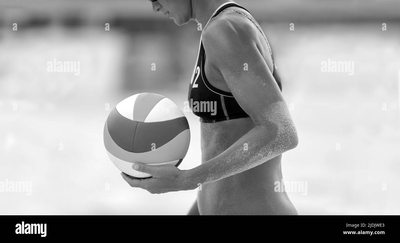 Un jugador de voleibol de playa se está Preparando para servir la pelota en formato de imagen en blanco y negro Foto de stock