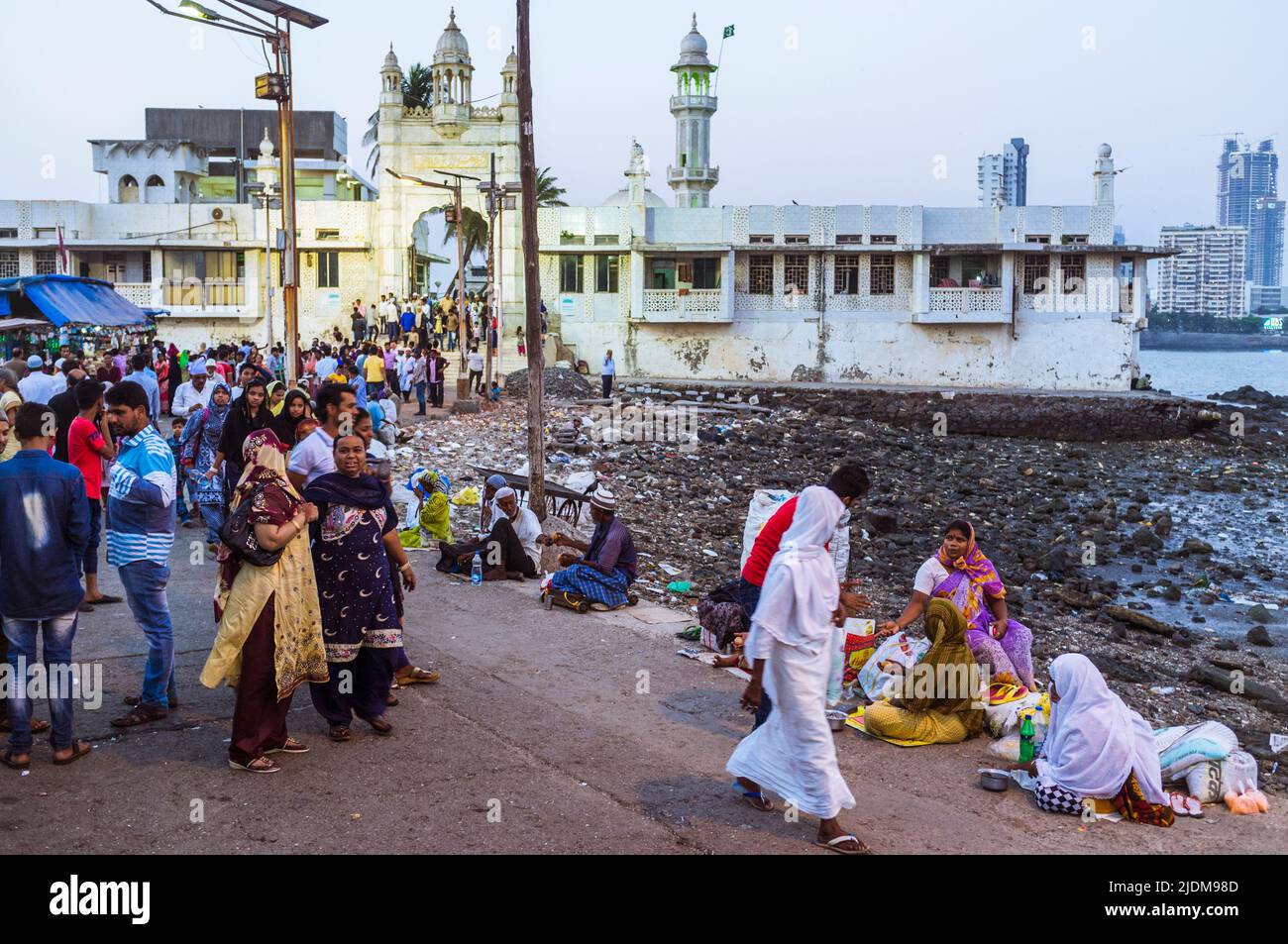 Mumbai, Maharashtra, India : Los peregrinos caminan pasando mendigos en la calzada que conduce al Haji Ali Dargah del siglo 19th y la mezquita que contiene la tumba Foto de stock