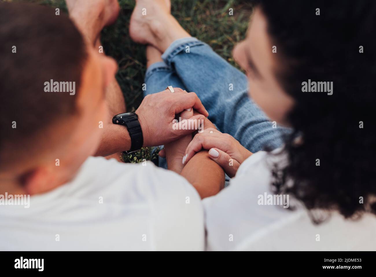 Close Up Back View of Man and Woman sosteniendo con las manos sentadas en la tierra al aire libre, Pareja de Edad Media en Amor Foto de stock