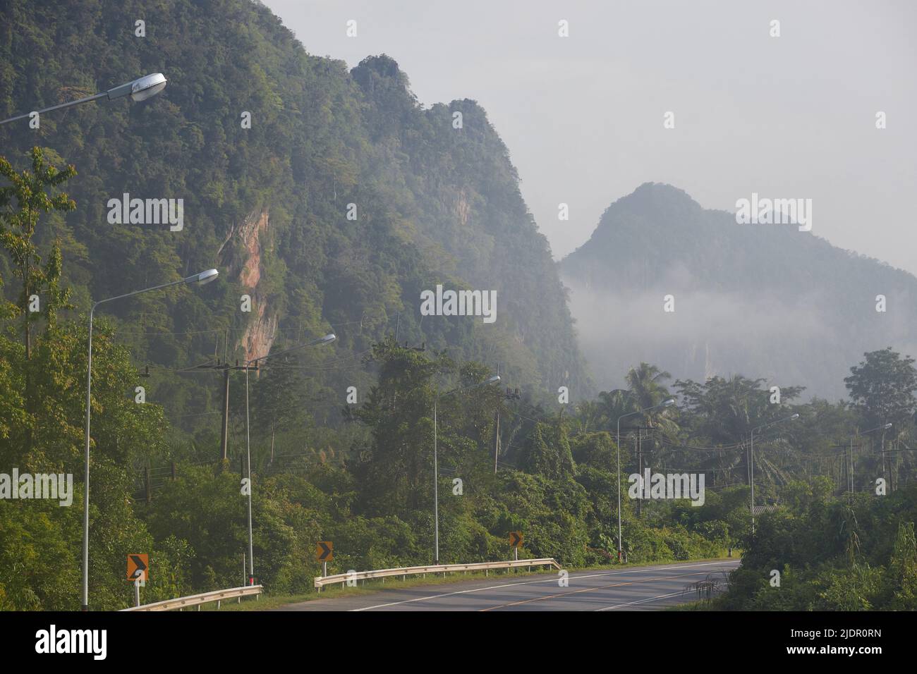 Asfalto camino a las montañas con niebla por la mañana Foto de stock