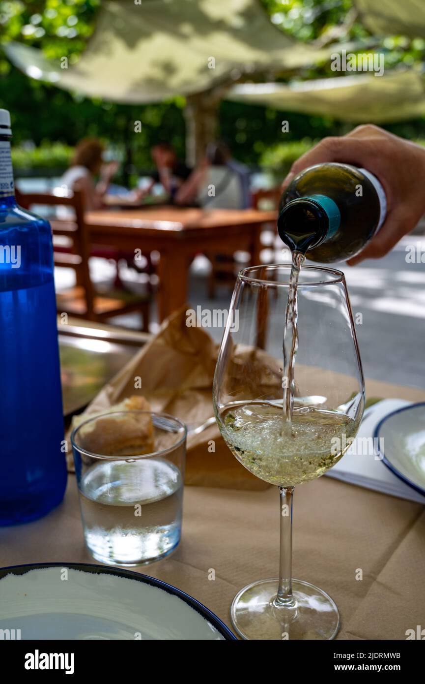 Verter en vaso de txakoli o chacolí Vino blanco muy seco y ligeramente  espumoso producido en el País Vasco español, servido al aire libre en  cafetería de Bilbao Fotografía de stock -