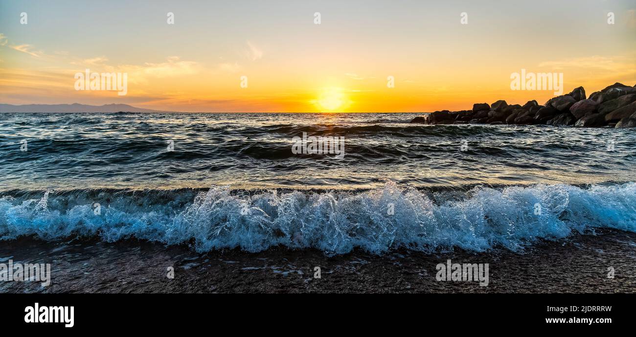 Una onda oceánica iluminada al amanecer en la orilla de la playa está en un formato de imagen de banner de alta resolución Foto de stock