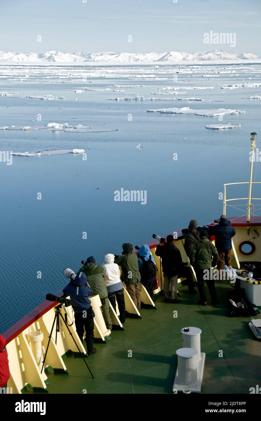 Eco-turistas y fotógrafos en el arco de la expedición vessle 'Estrella Polar' viendo eventos emocionantes en el hielo del noroeste Spitsbergen Foto de stock