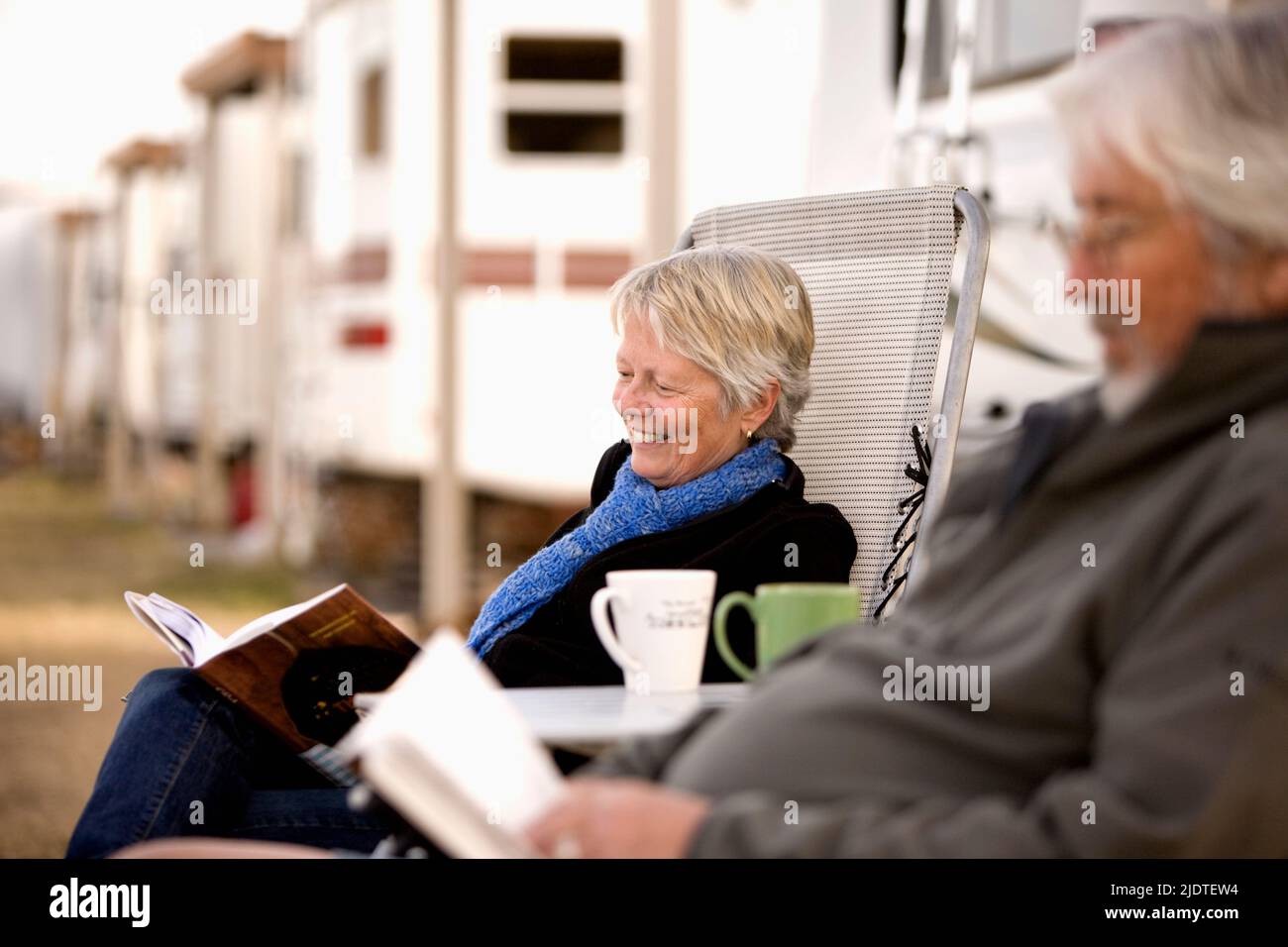 Pareja madura leyendo y bebiendo café fuera de su RV aparcado para el invierno en Parker, cerca del lago Havasu. Foto de stock
