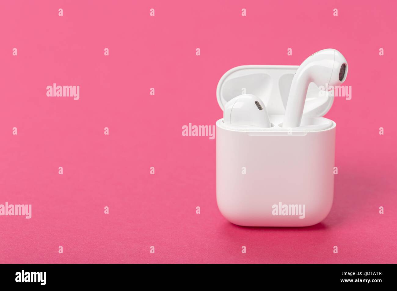 Modernos auriculares inalámbricos bluetooth ® con estuche de carga sobre  fondo morado-rosa Fotografía de stock - Alamy