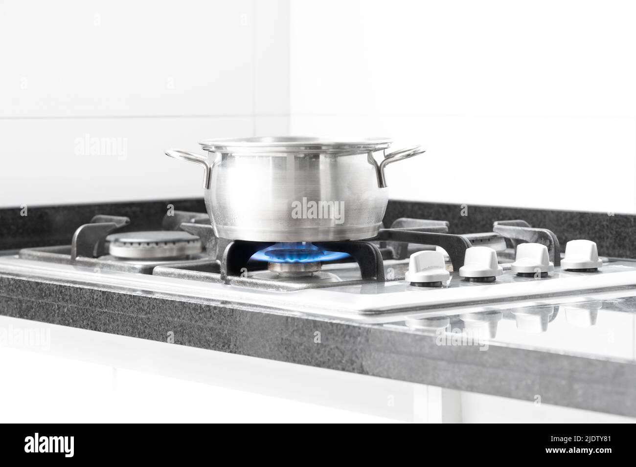Olla de cocción en la estufa con una llama de gas natural azul Foto de stock