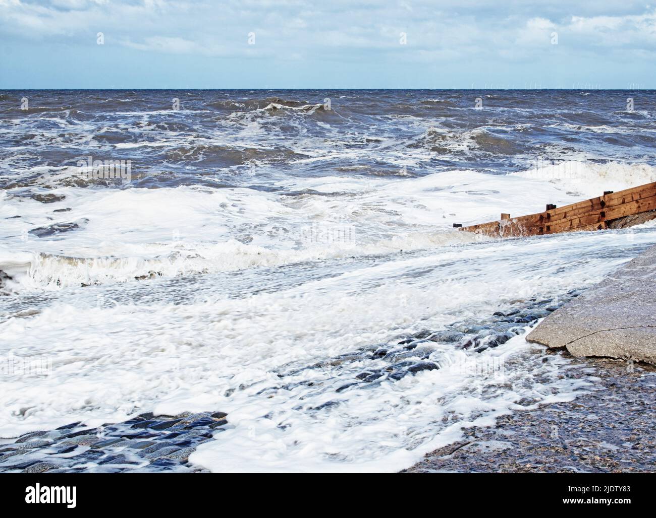 Una marea espumosa y las olas golpean suavemente en la costa en Cleveleys, Fylde Coast, Lancashire, Reino Unido Foto de stock