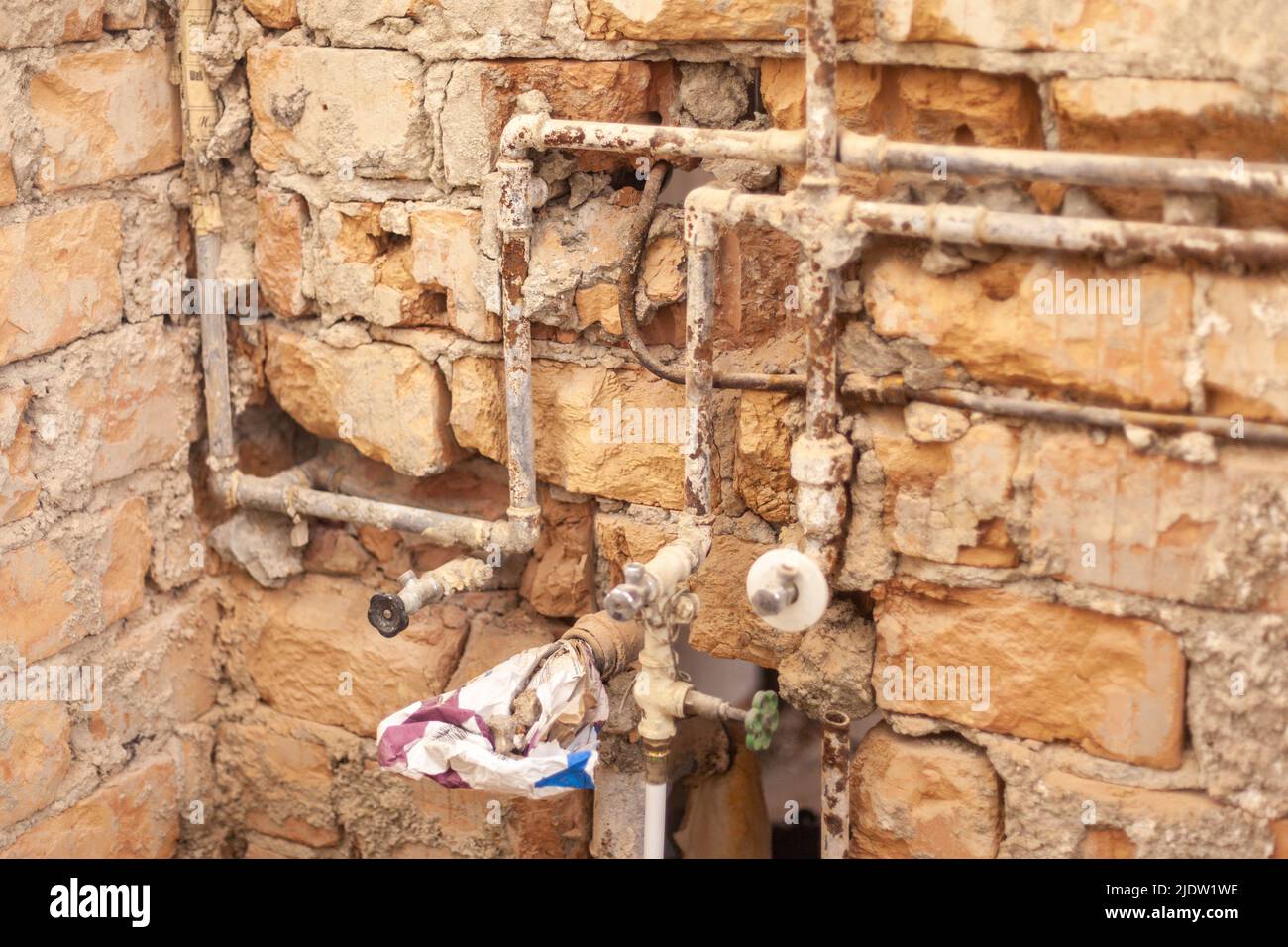 Tuberías de agua oxidadas y tuberías de aguas residuales antiguas expuestas en un edificio antiguo Foto de stock
