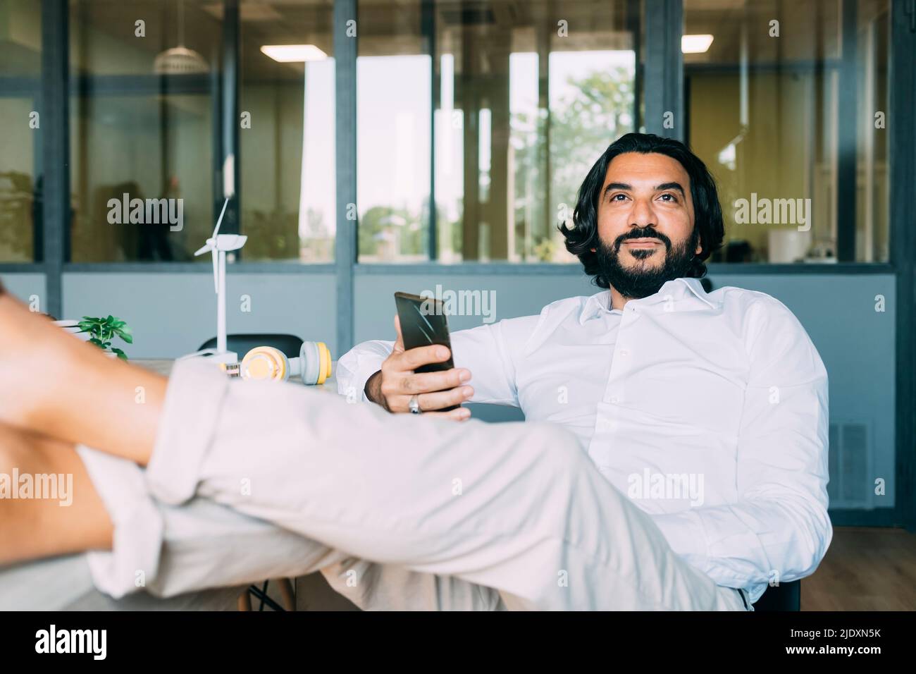 Hombre de negocios con teléfono móvil en tiempo de descanso en el lugar de trabajo Foto de stock